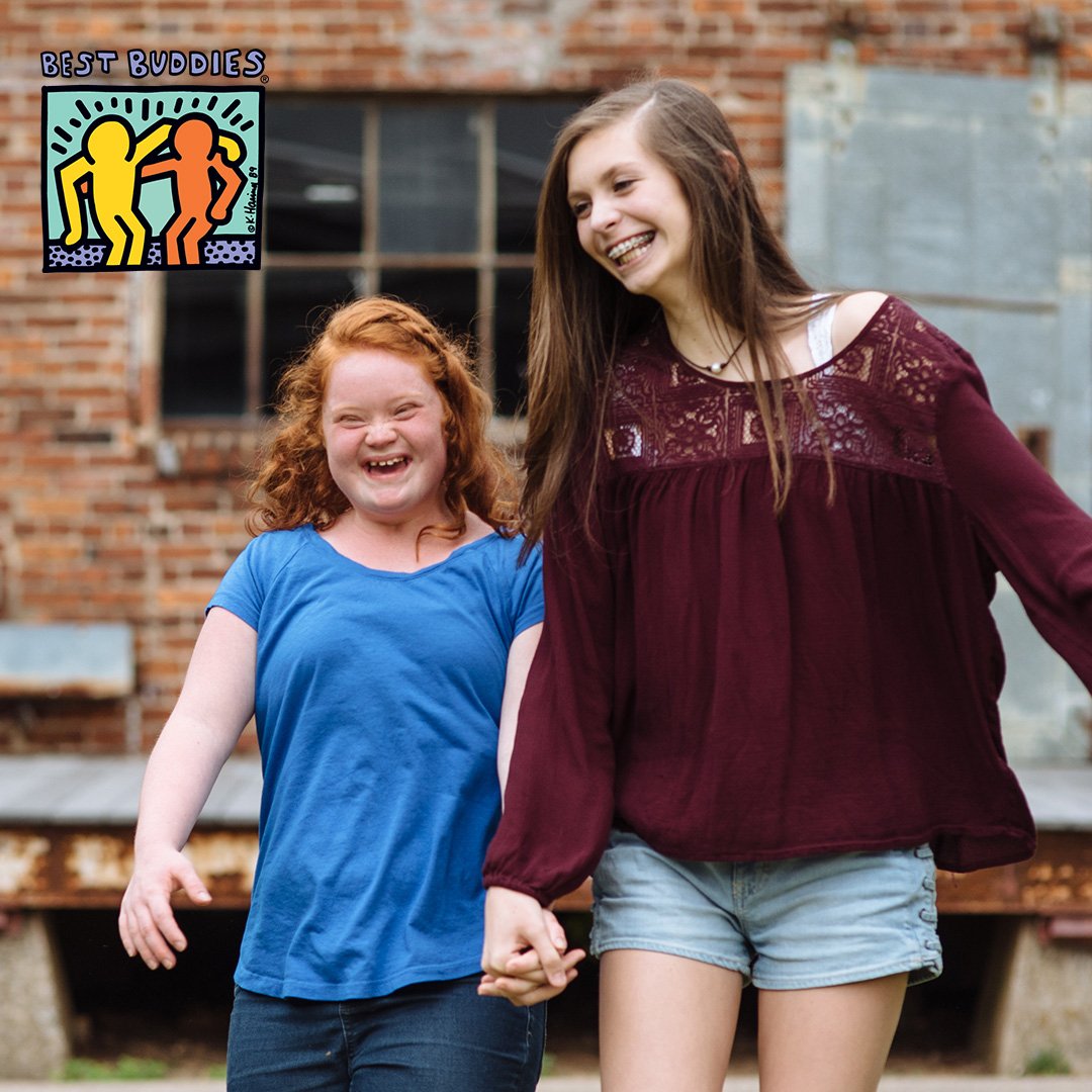 Buddy Pair walking down the street holding hands and smiling